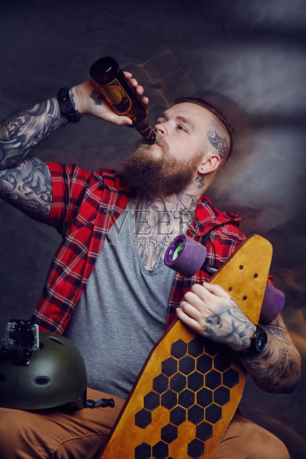 胡子纹身的男人喝啤酒。照片摄影图片