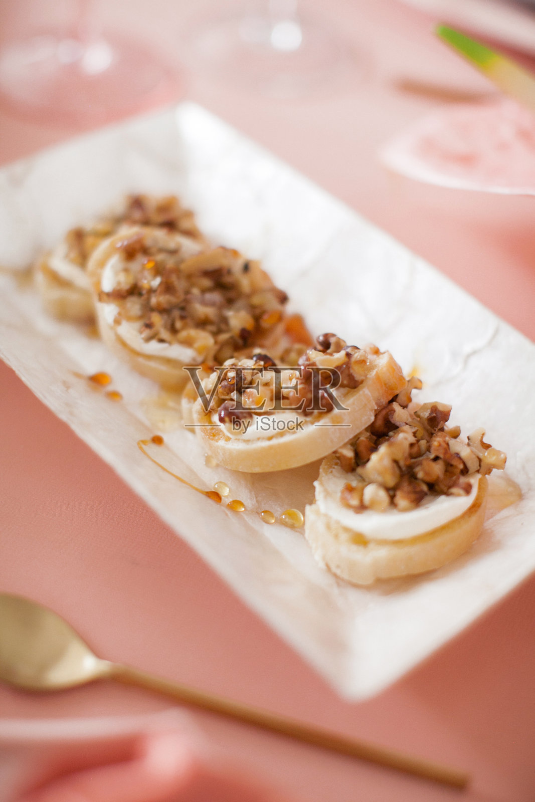 节日装饰。淡粉色搭配金色餐具。奢华的婚礼、派对、生日。焦糖梨配核桃和蜂蜜照片摄影图片