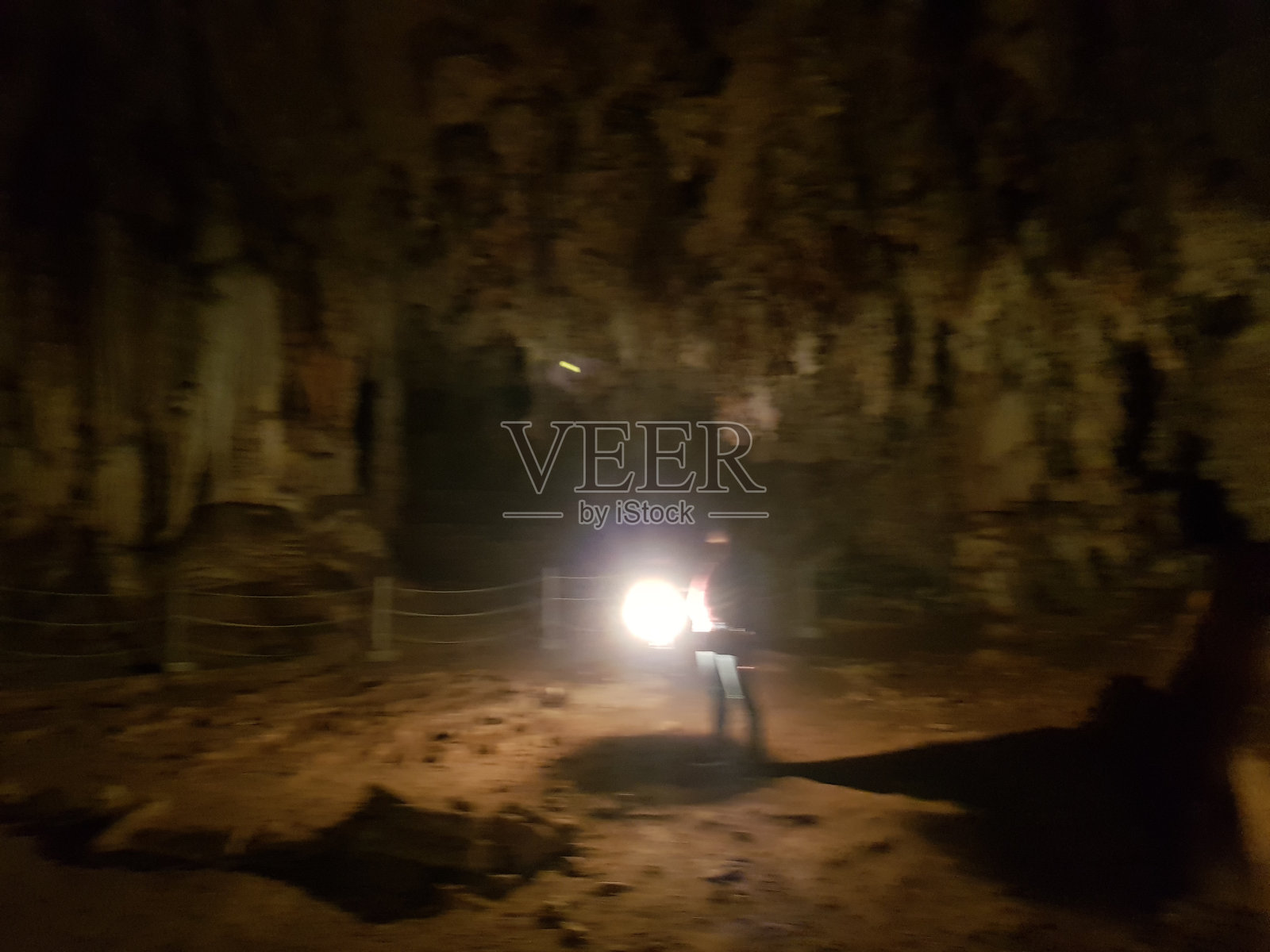 亚洲女子背包客在黑暗的岩洞中提着灯笼探索世界。照片摄影图片