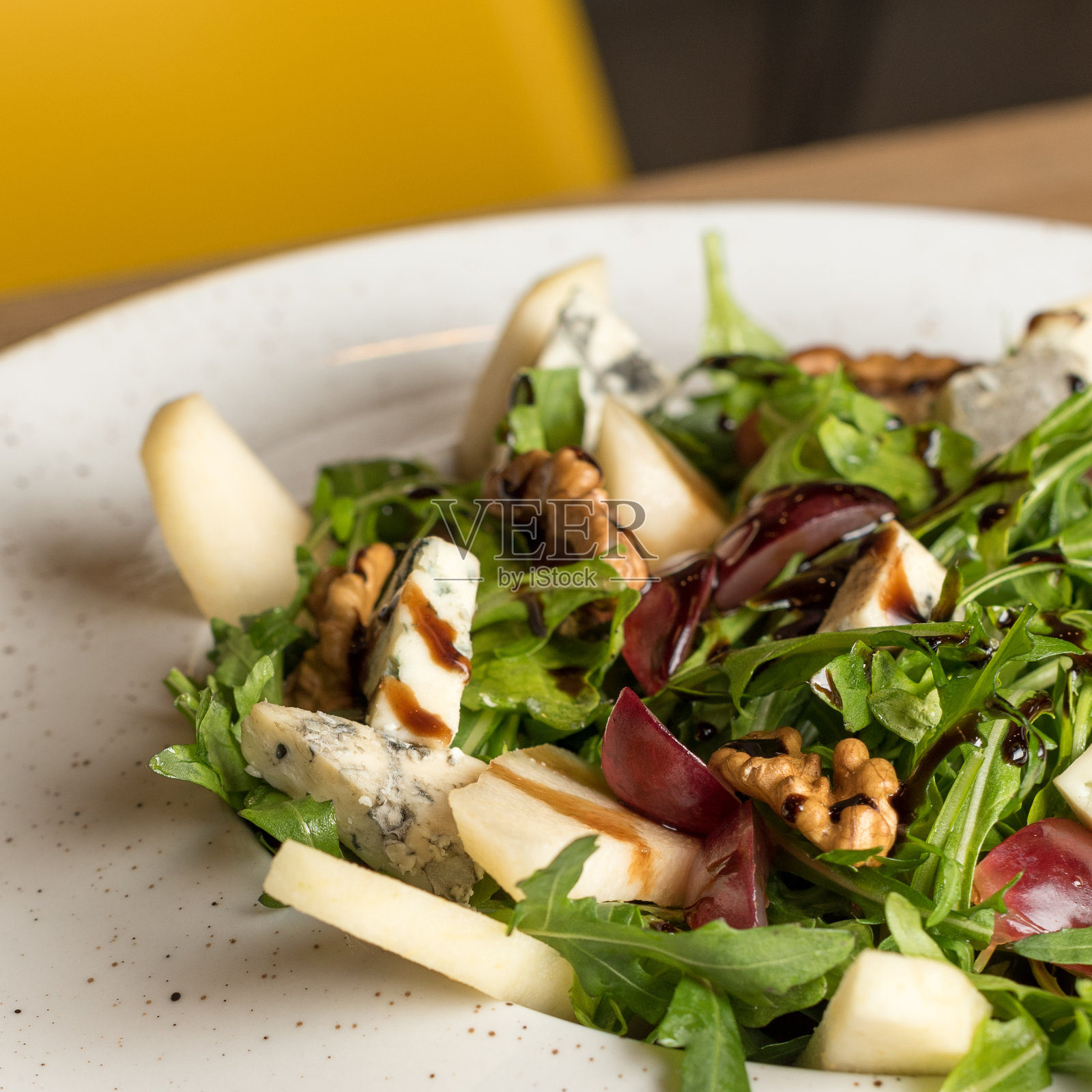 配奶酪、葡萄、核桃和美味酱汁的绿叶蔬菜沙拉。健康的减肥食品照片摄影图片