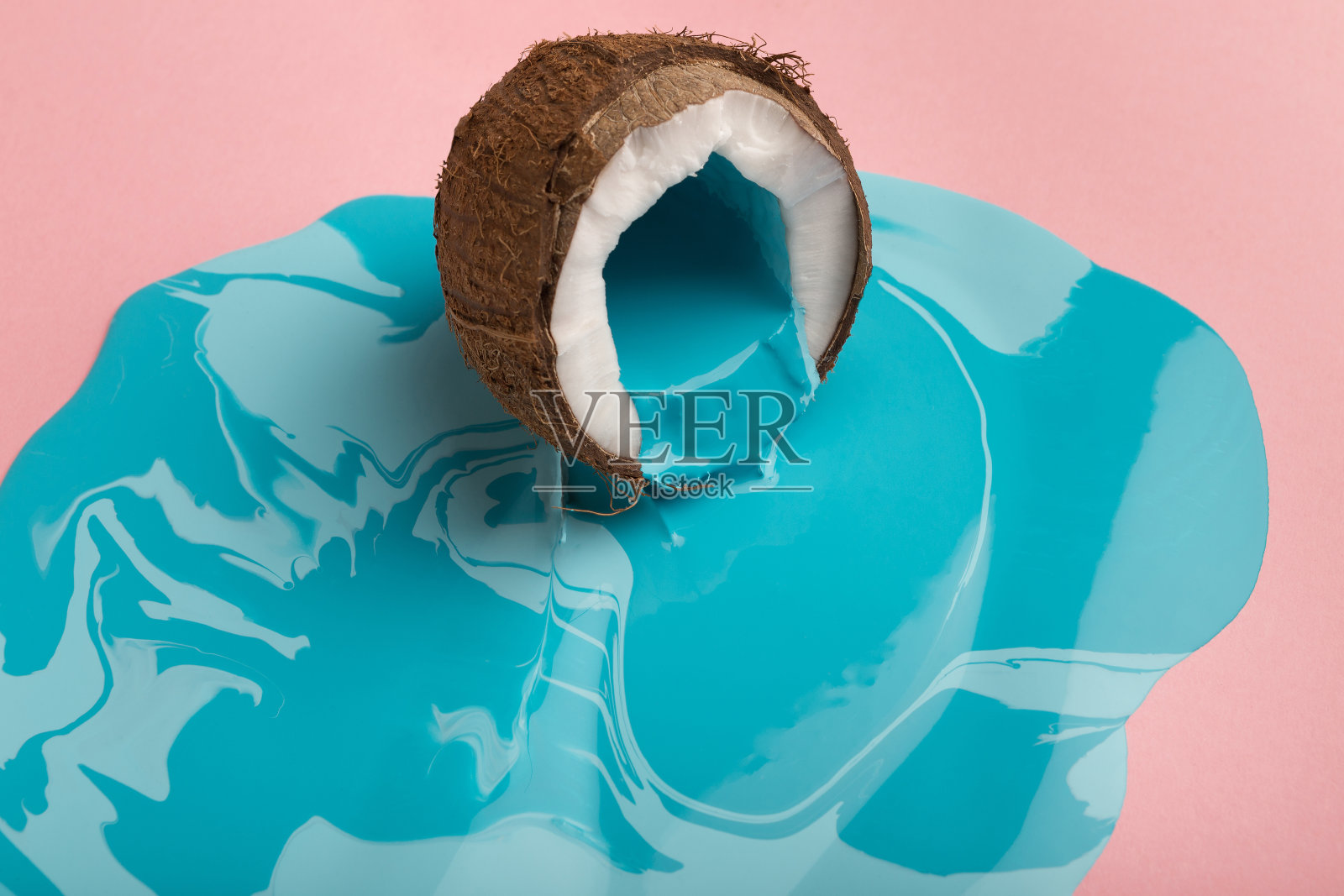 粉红色的背景上，椰子上的蓝色油漆正在脱落照片摄影图片