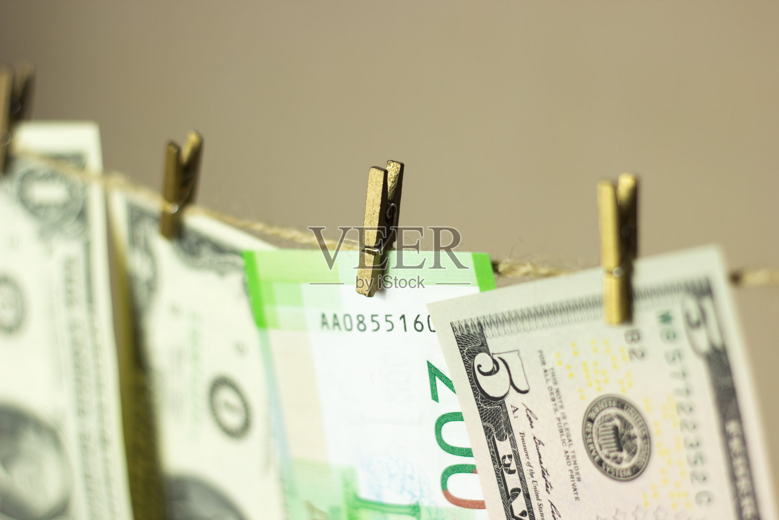 美元挂在晒衣绳上，晒衣夹附在金色的背景上照片摄影图片