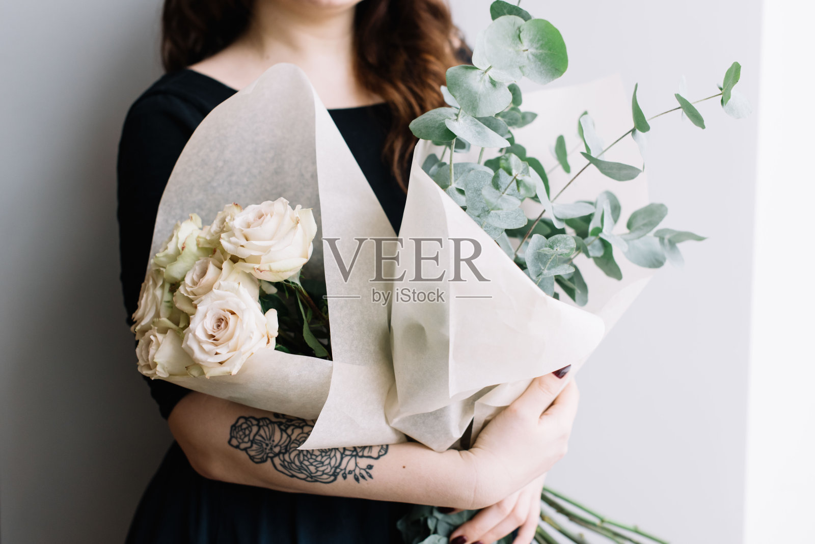 VORONEZH/俄罗斯- 2018年2月2日:美丽的年轻白人女子，手握两束鲜花(分别是玫瑰花束和桉树花束)照片摄影图片