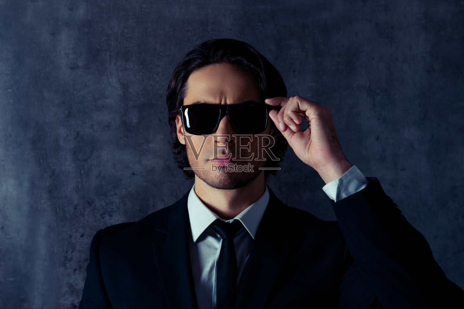 严肃的保镖触摸他的黑眼镜的肖像照片摄影图片