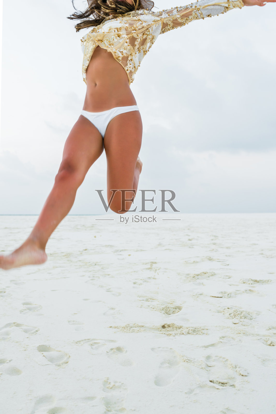 美丽无忧无虑的女人在沙滩上的空中跳跃照片摄影图片