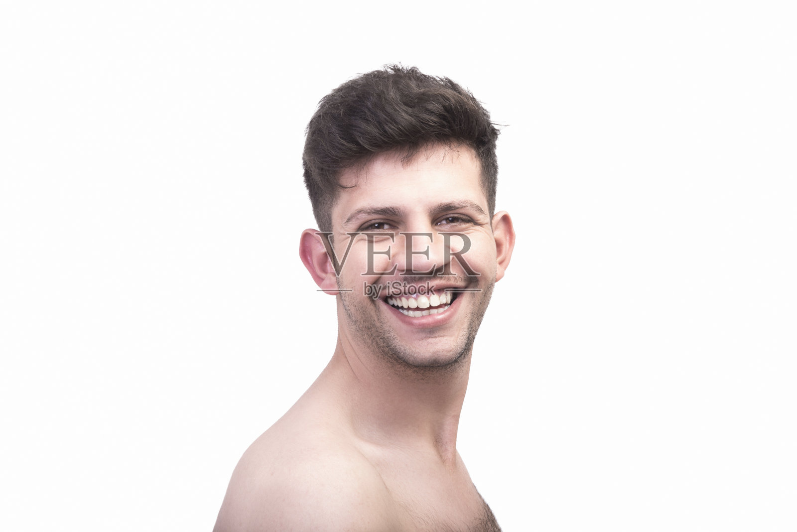 年轻男子的肖像看着他的肩膀上的照相机笑在一个白色的背景照片摄影图片