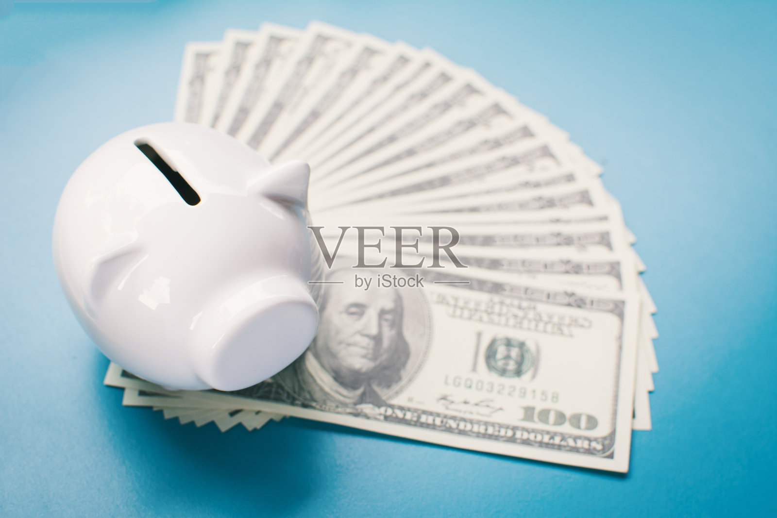 白色储蓄罐和蓝色背景的钱，储蓄概念照片摄影图片
