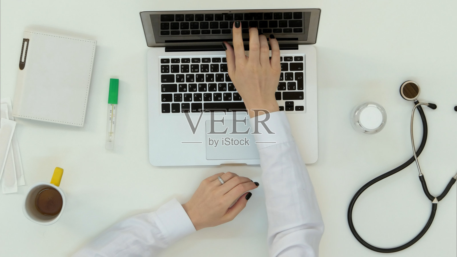 女医生用听诊器在笔记本电脑上打字照片摄影图片