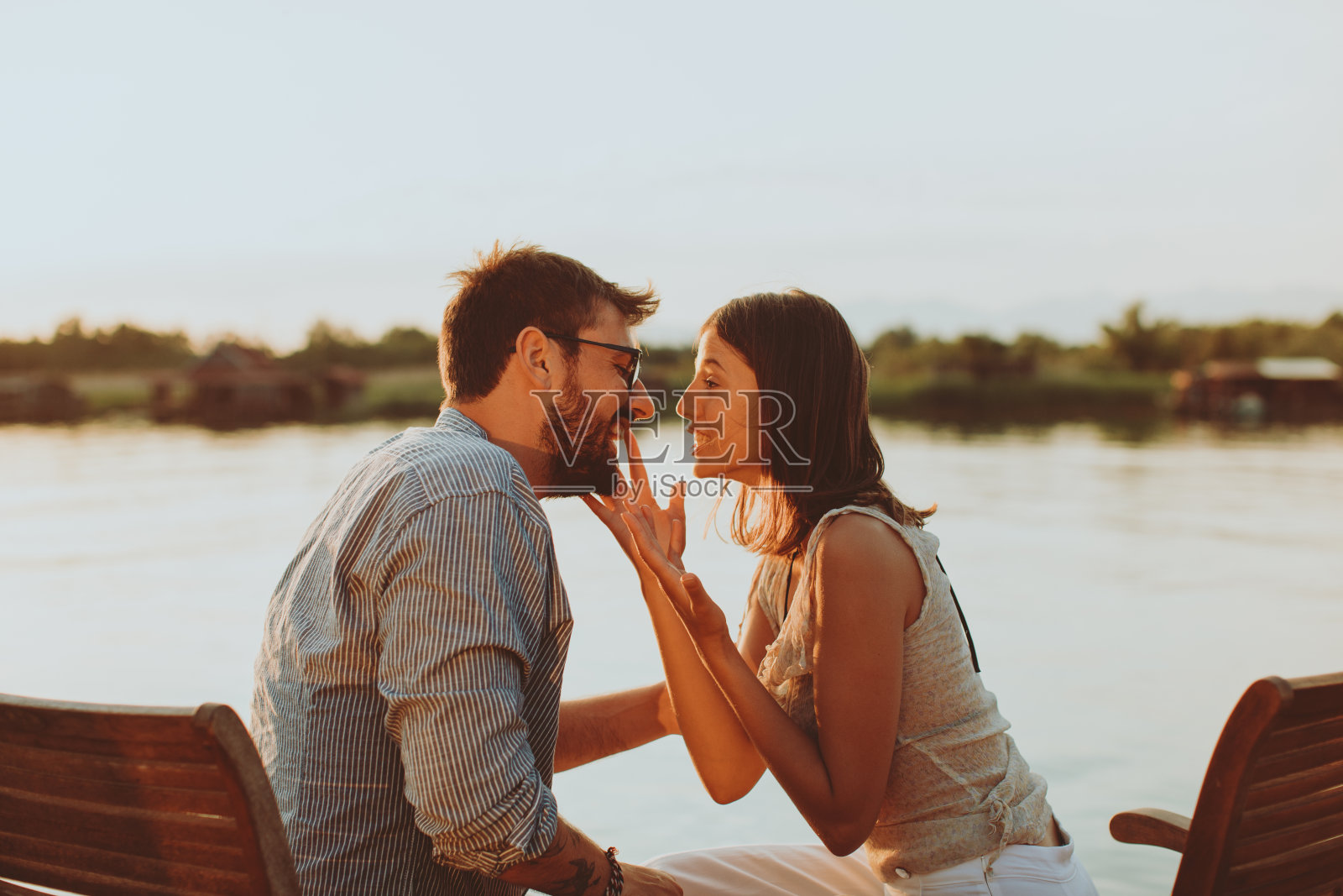 日落时分，一对年轻的恋人在河边调情照片摄影图片