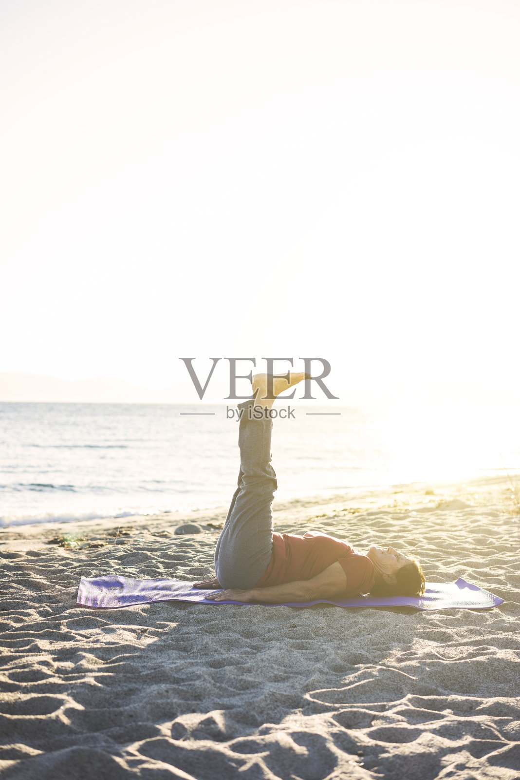 老年妇女在海滩上做瑜伽照片摄影图片