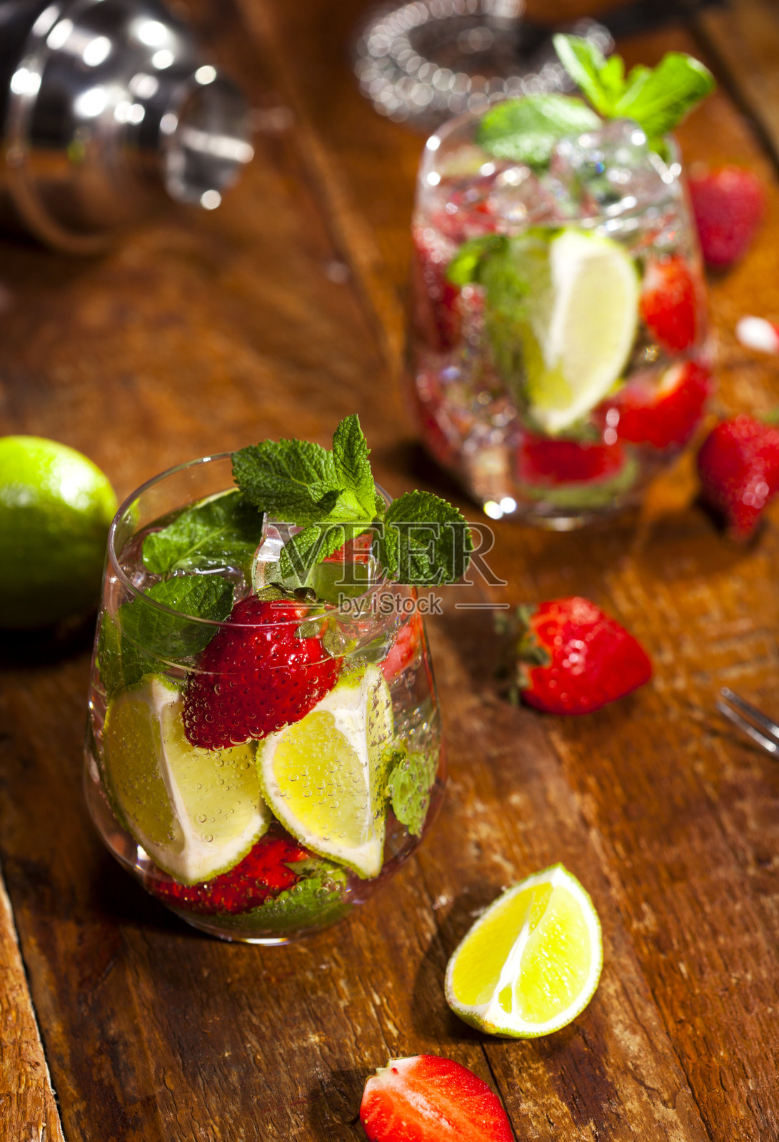 草莓、薄荷、青柠和冰块放在木质吧台上的夏日冷饮。鸡尾酒与新鲜水果的特写。照片摄影图片