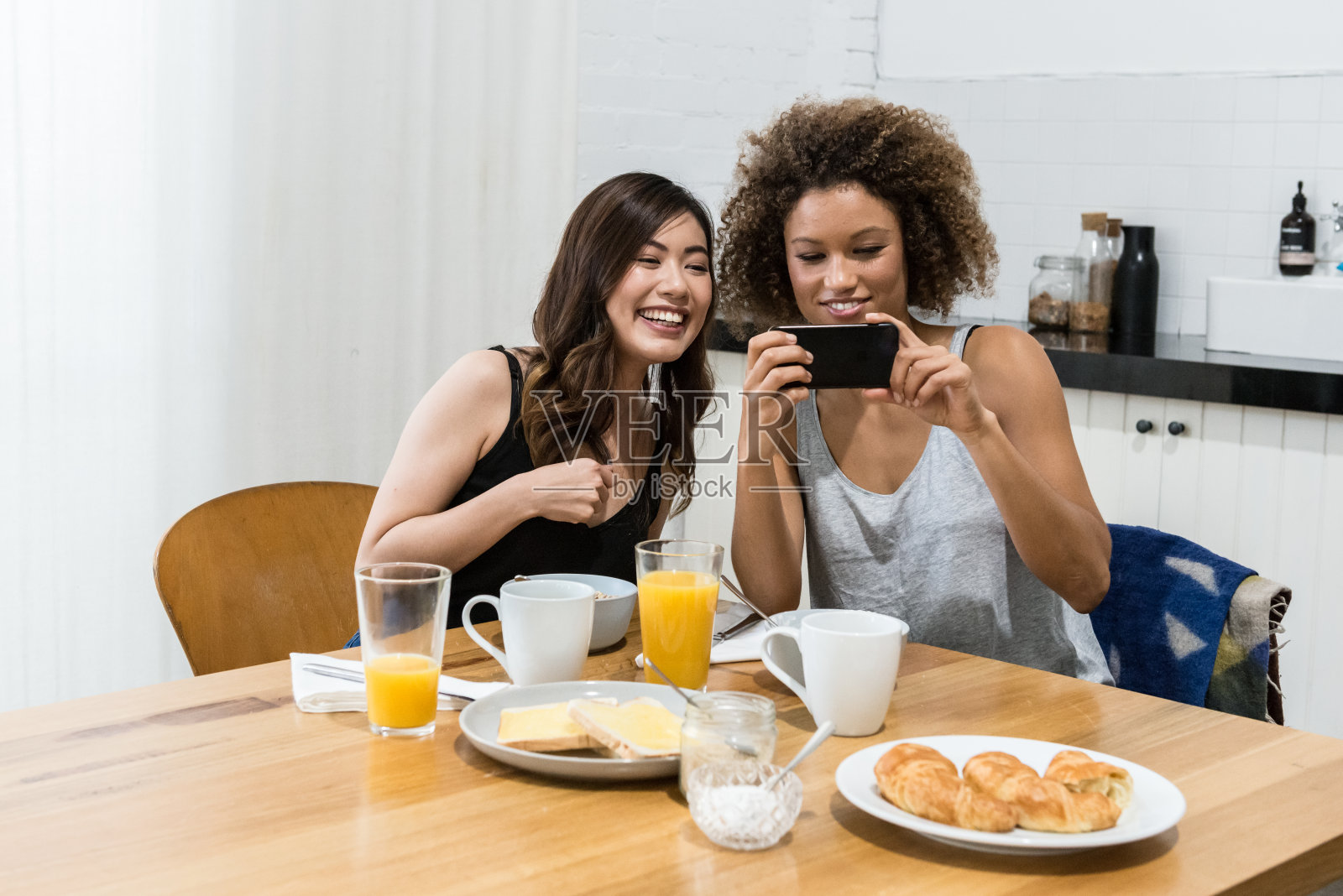 两个年轻女人在厨房里聊天发短信照片摄影图片