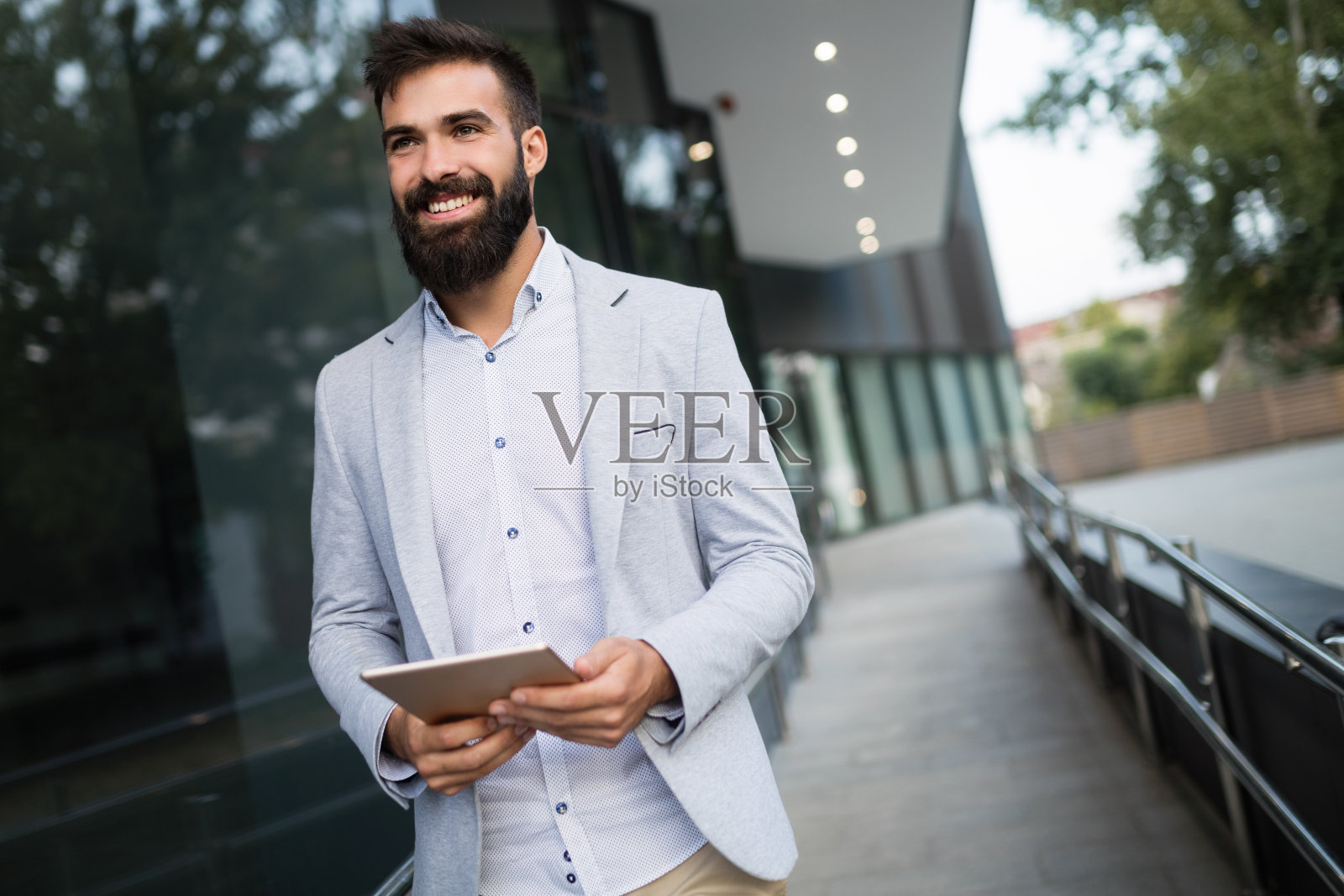 微笑的商人坐在长凳上，拿着数码平板电脑照片摄影图片