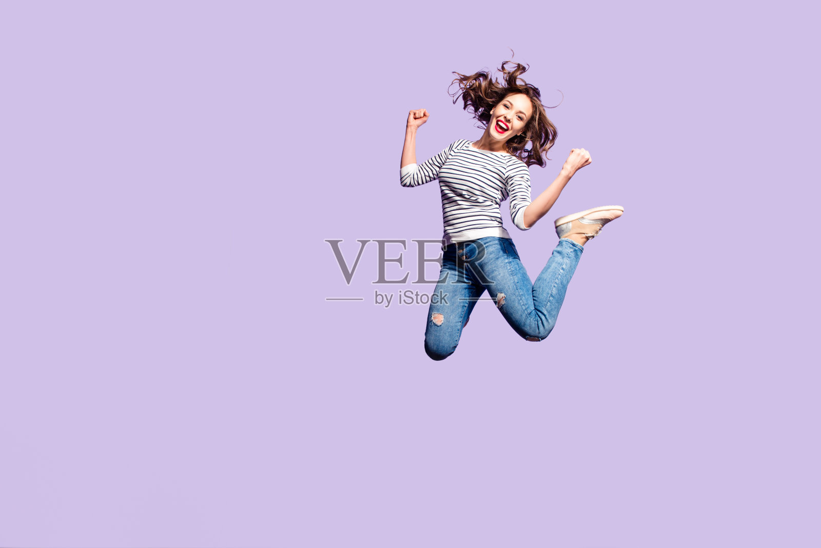 成功的疯狂女孩庆祝胜利的肖像跳跃在空中举起拳头大喊孤立在紫罗兰的背景，充满活力的人在行动的概念照片摄影图片