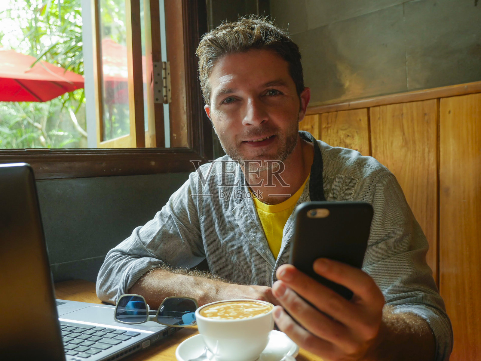 年轻、快乐、成功的千禧男，在网吧工作，带着笔记本电脑和手机，轻松的企业家和现代数字游牧的工作理念照片摄影图片