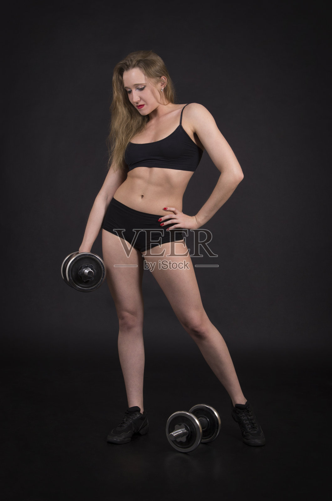 一位年轻女子用哑铃健身。照片摄影图片