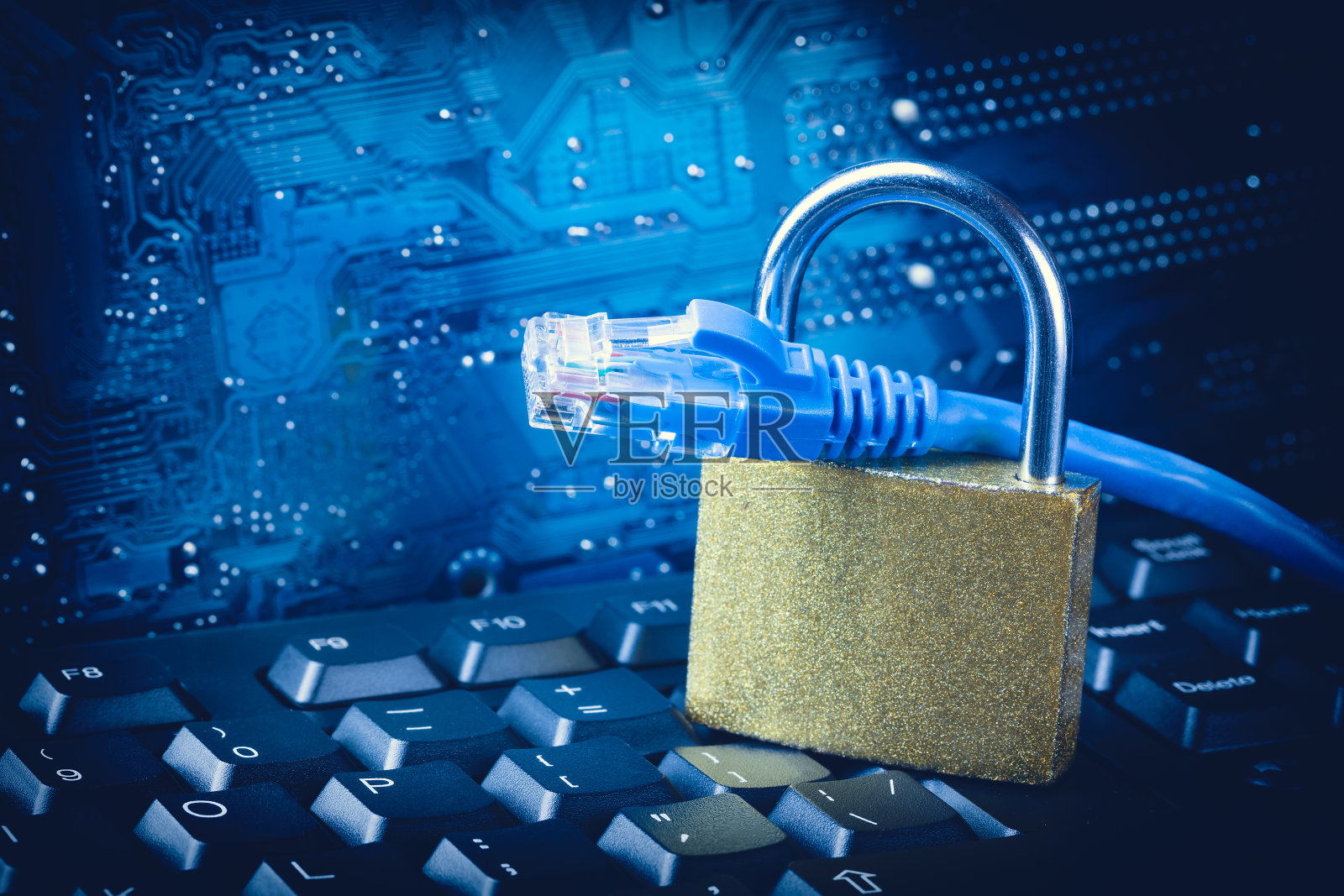 用以太网网线将挂锁紧靠在蓝色电路板主板的背景上。互联网数据隐私信息安全概念。照片摄影图片