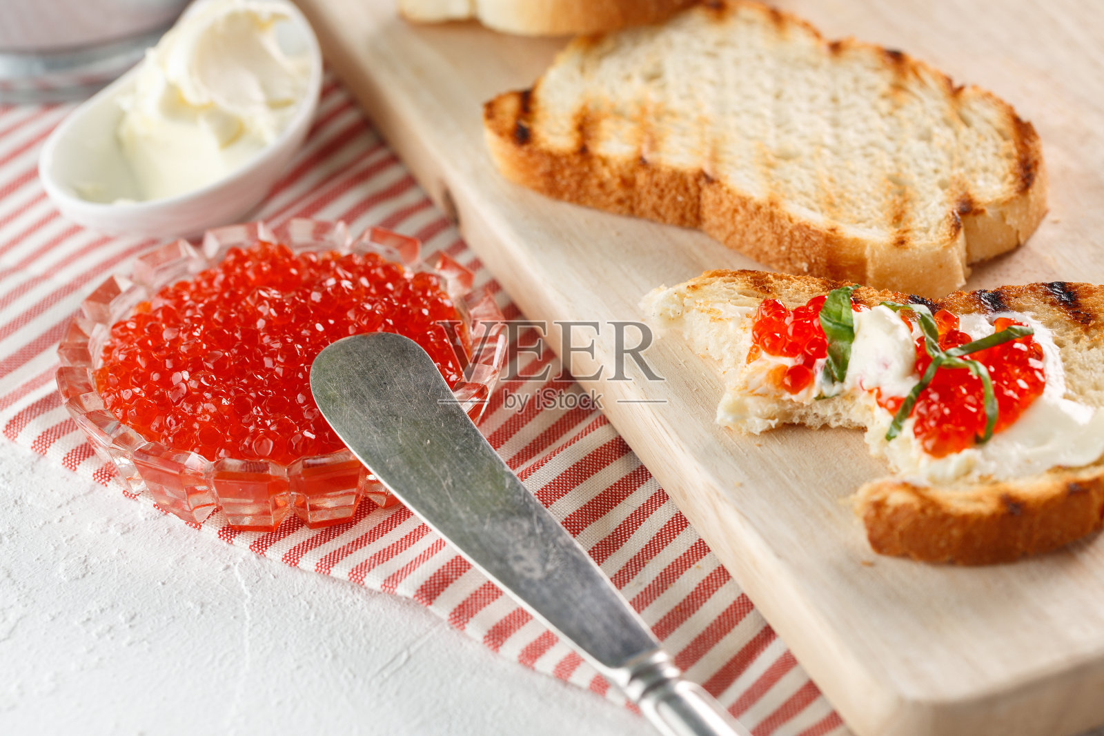 烤面包用黄油和红鱼子酱放在木砧板上照片摄影图片