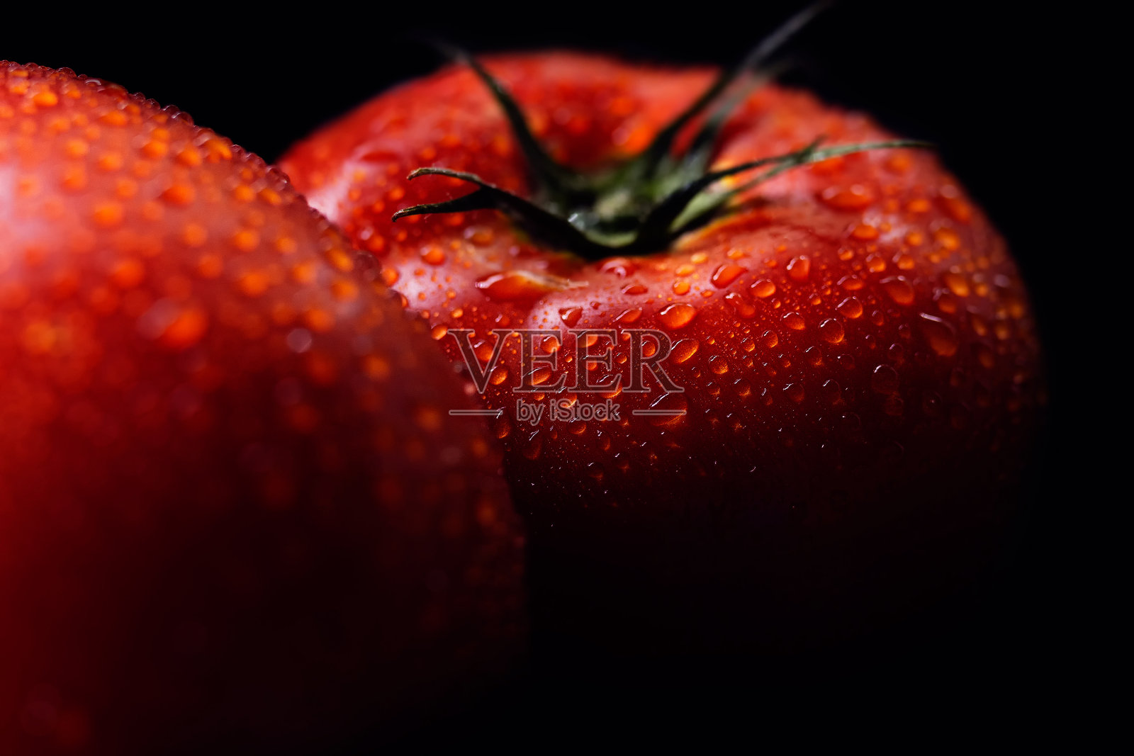 两个成熟的红色西红柿，洗过了，上面还有水滴，放在黑色的背景上照片摄影图片