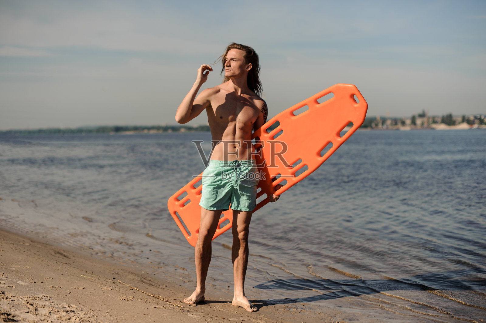 英俊性感的海滩救生员站在沙滩上救生设备照片摄影图片