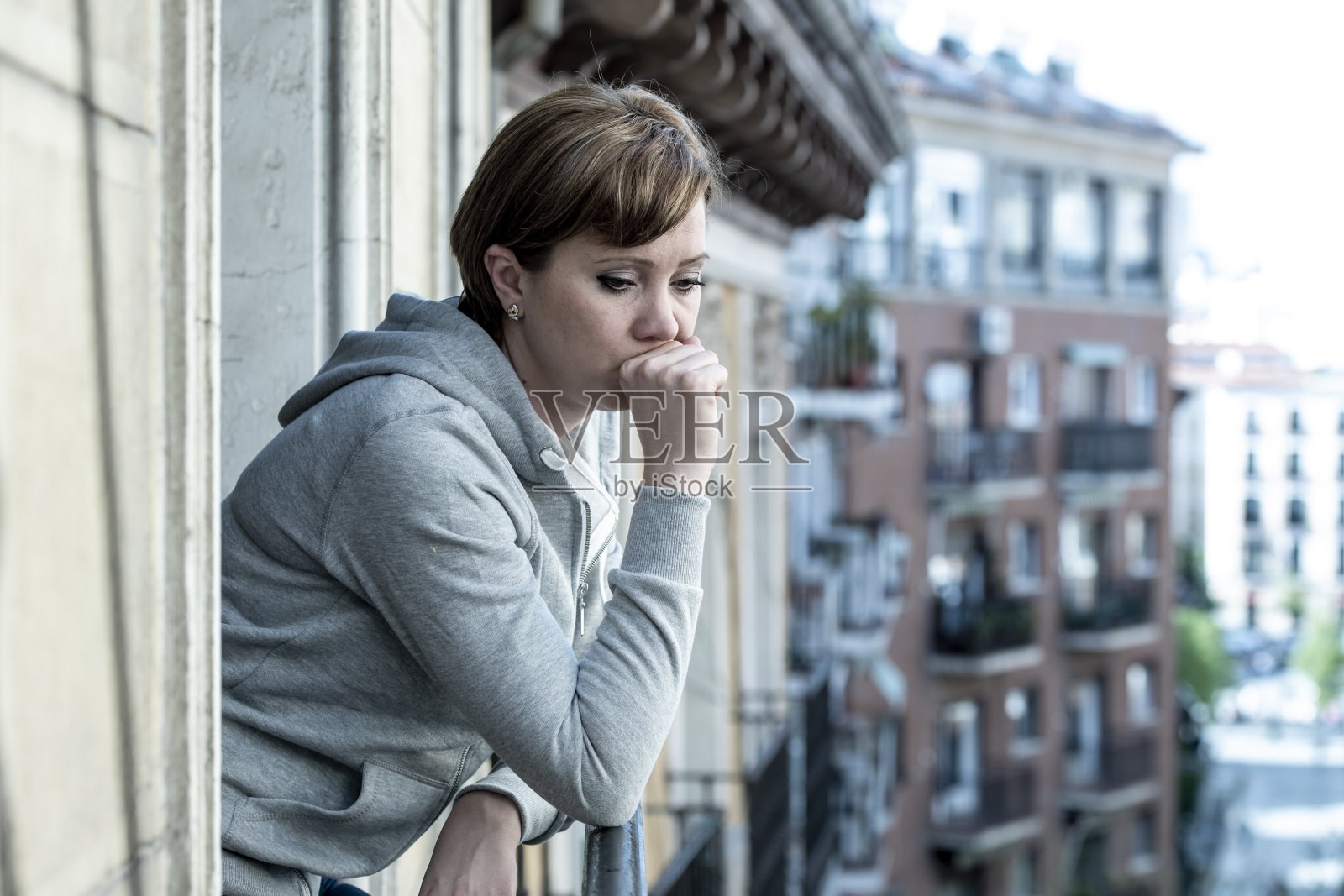 年轻的白人妇女在阳台上情绪低落地沉思，患有抑郁症和焦虑症照片摄影图片