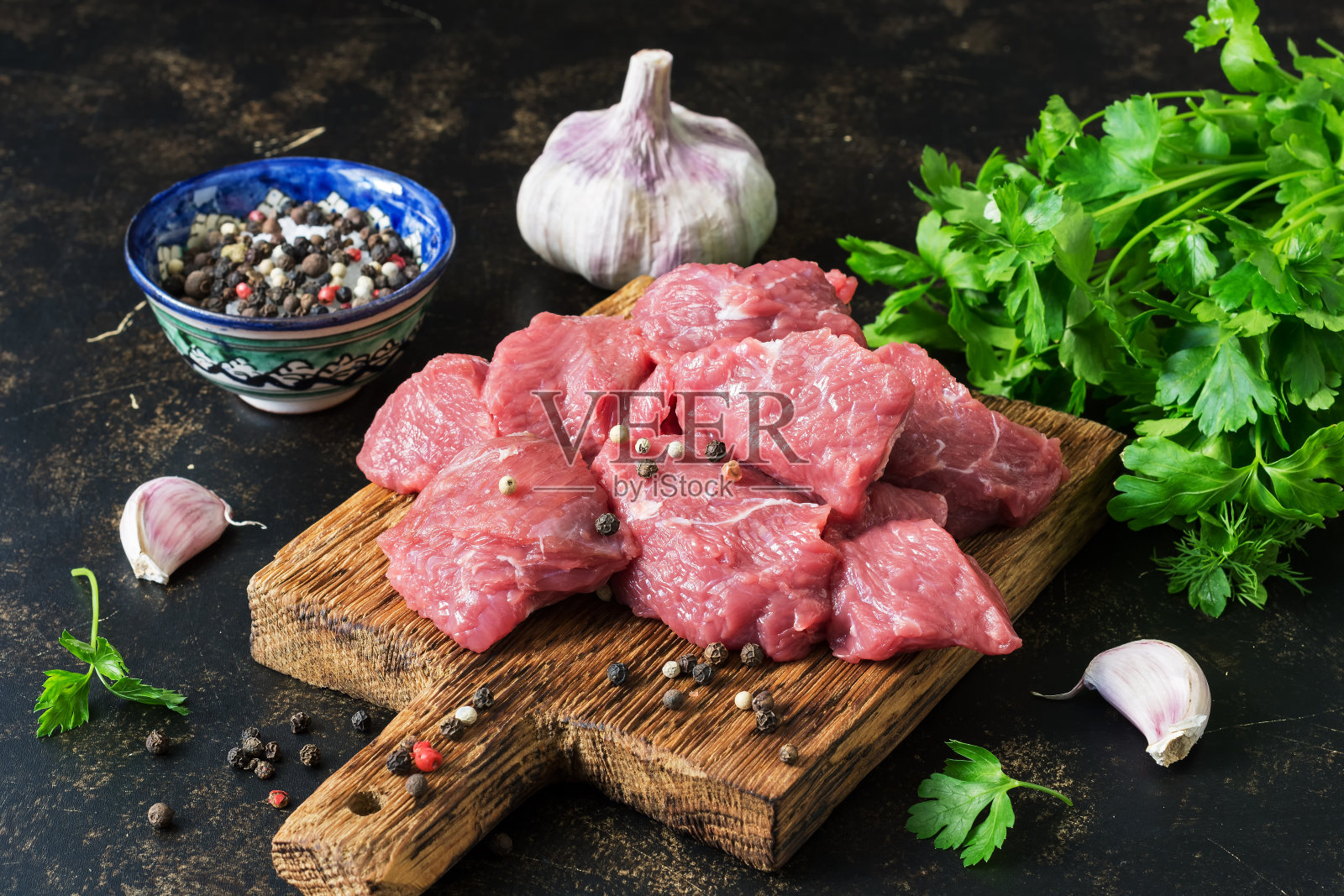 新鲜的生牛肉块与香草和香料放在砧板上。有选择性的重点。照片摄影图片