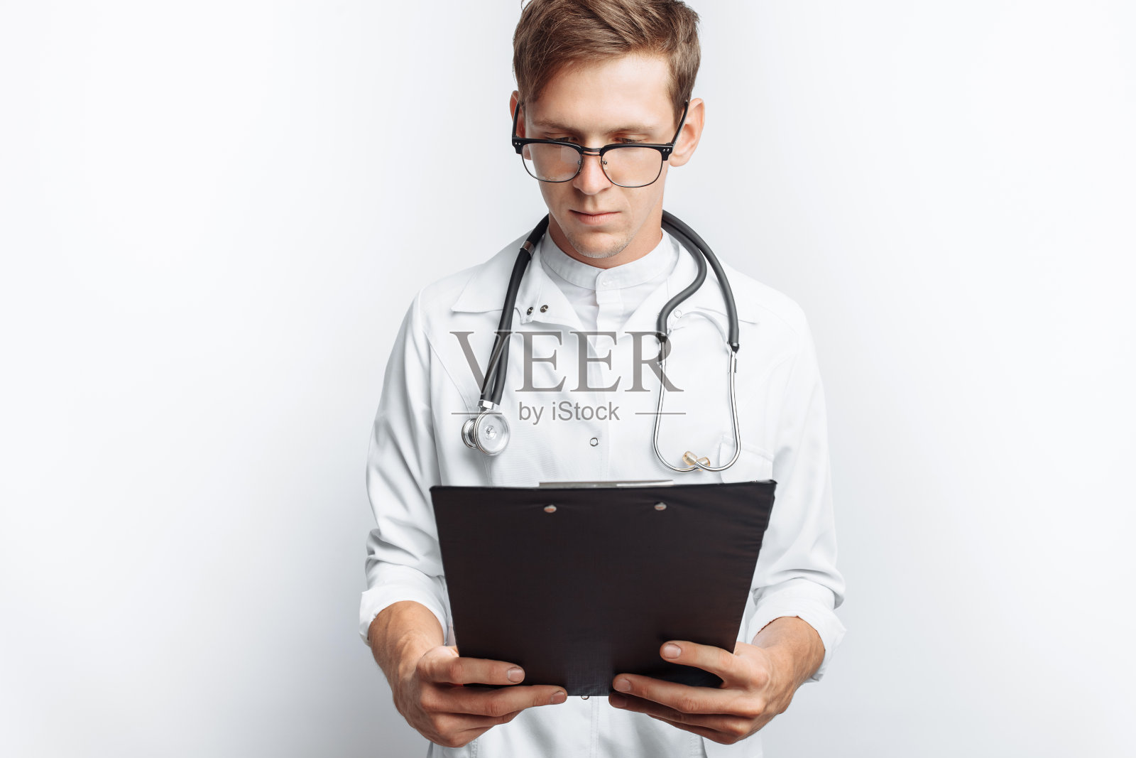 医生在文件中做笔记，一个年轻的学生手里拿着一个文件夹，在白色的背景上照片摄影图片