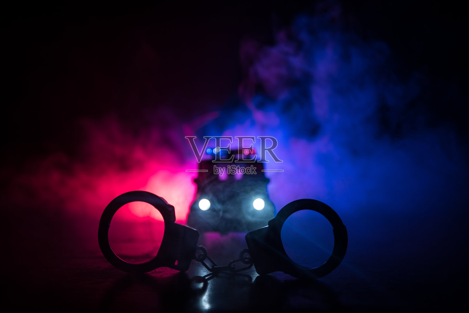 带着手铐在晚上的人行道上，还有警车的灯光照片摄影图片