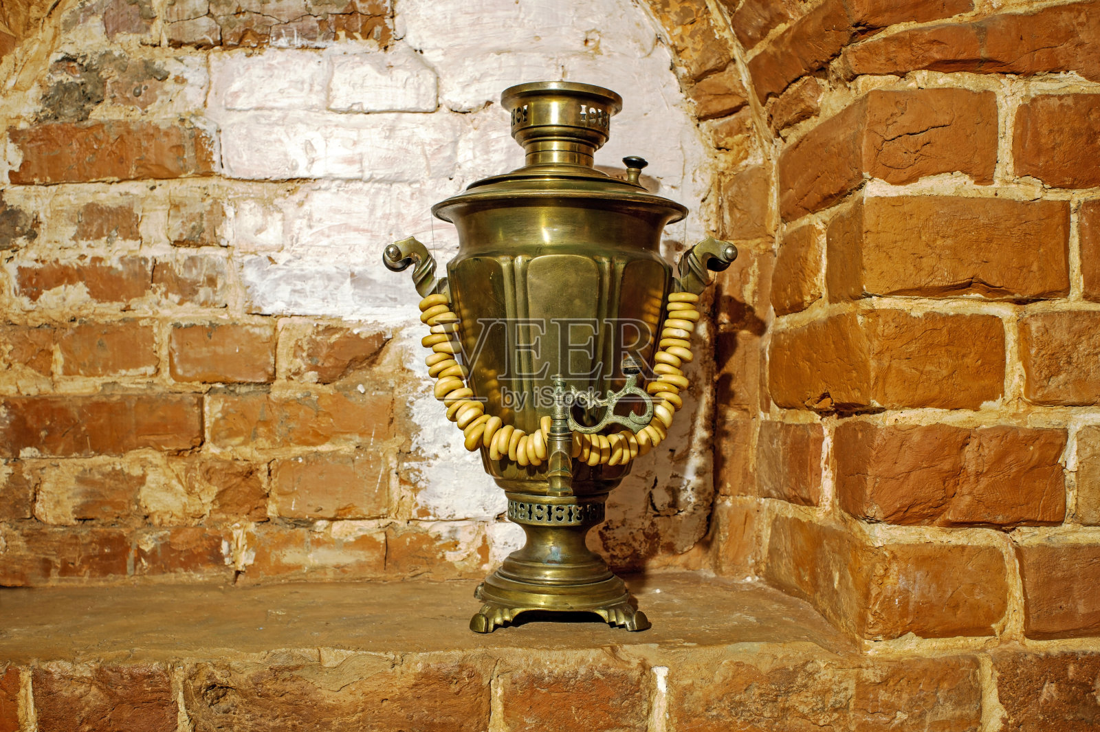 古老的俄罗斯铜制茶炊和面包圈，背景是一个红砖烤箱。背景、怀旧、复古照片摄影图片