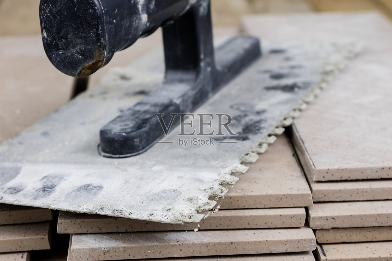 铺在地板上的瓷砖。建筑工人用的配件和材料摆放在木制的工作台上。暗的背景照片摄影图片