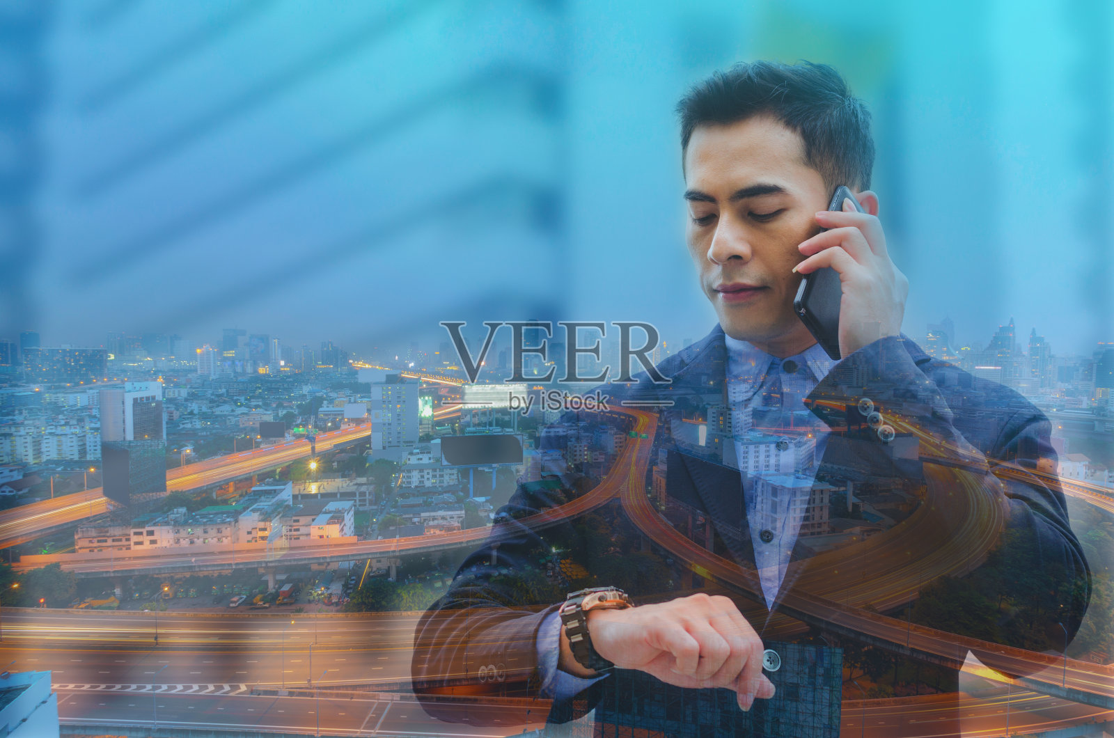 双重曝光有吸引力的英俊商人使用智能手机说话和看智能手表在户外夜景背景。技术交流的概念。照片摄影图片