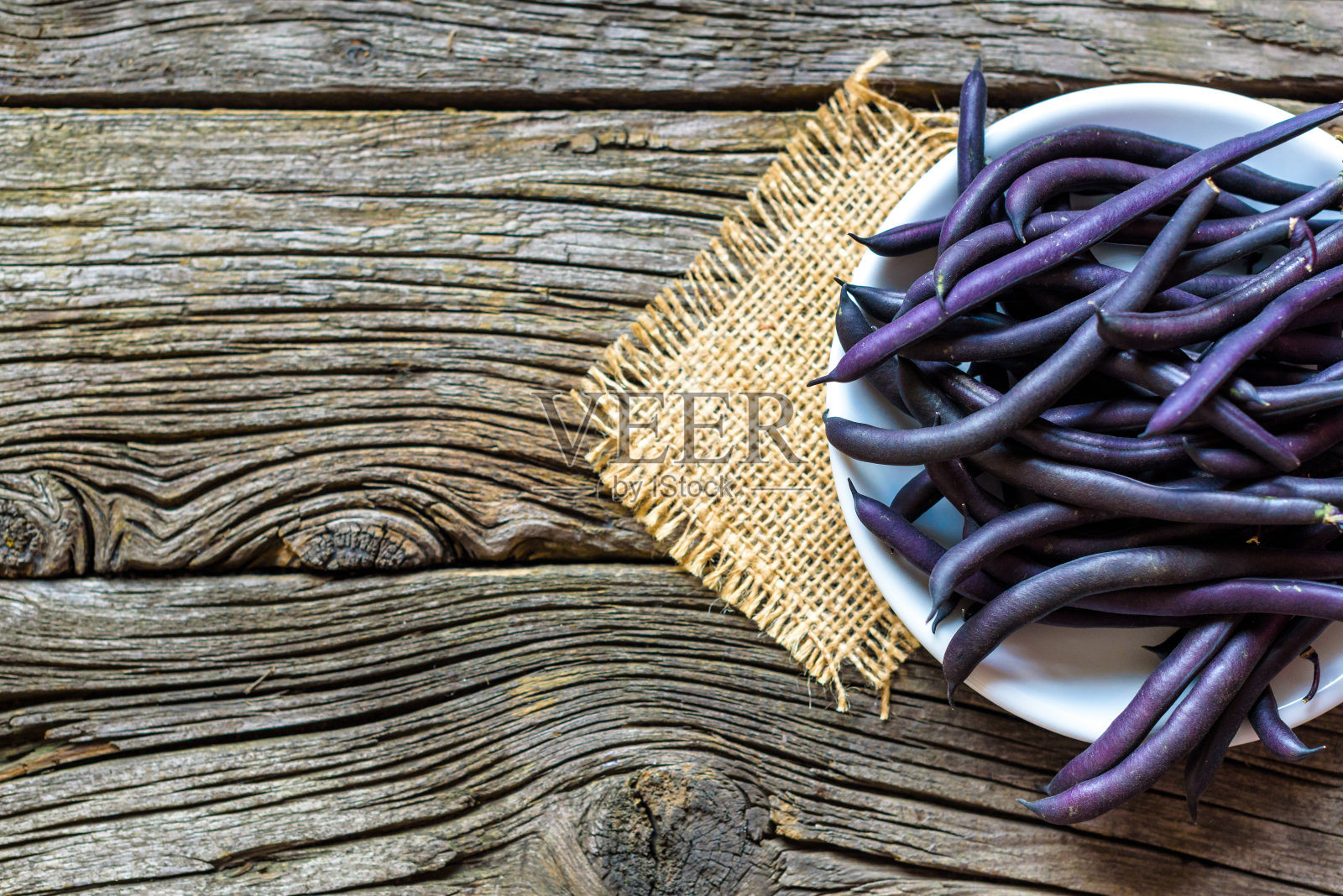 木质背景上的木盘上的紫色菜豆照片摄影图片