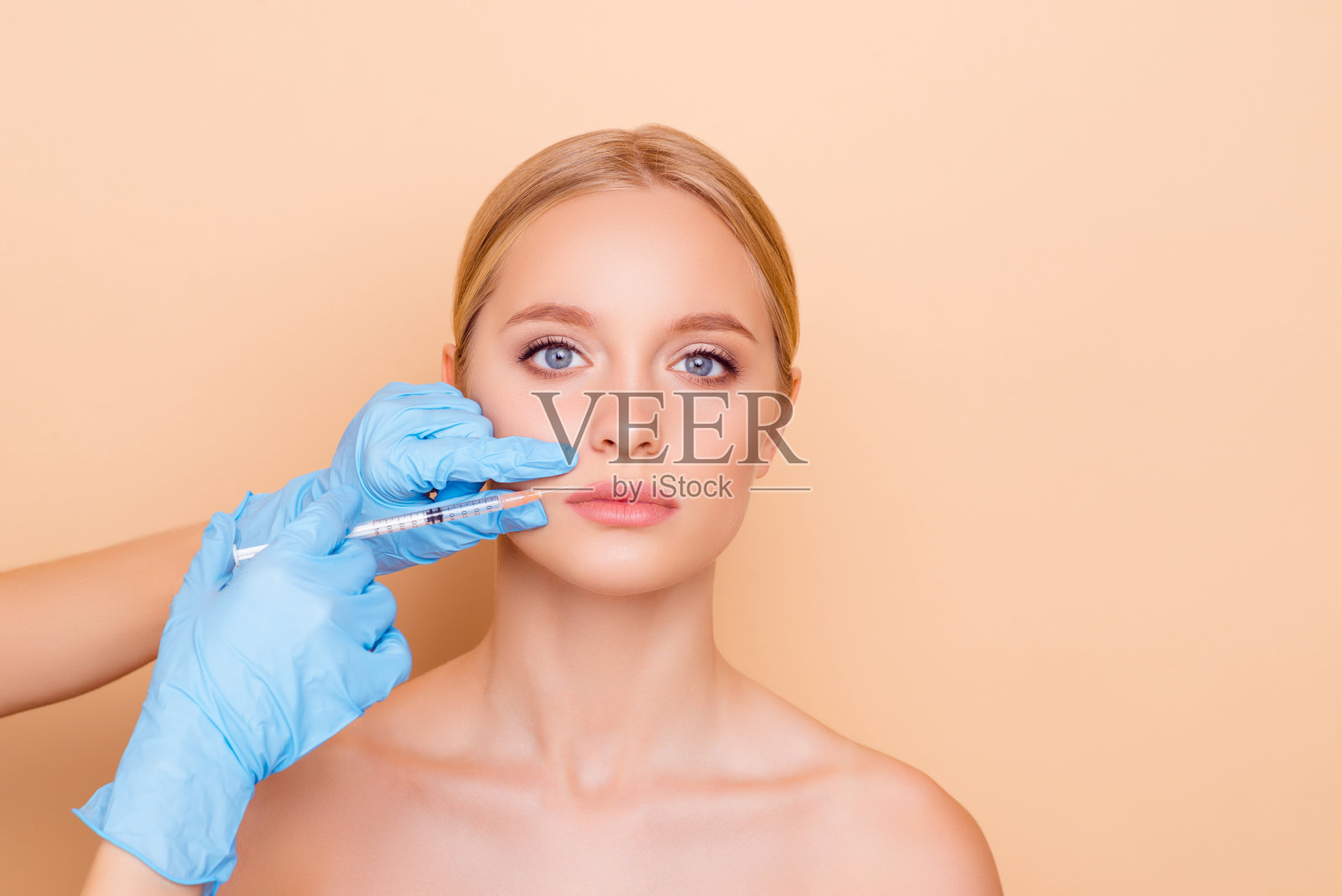 完美健康的幸福概念。迷人的漂亮的模特得到化妆品肉毒杆菌注射在嘴唇看相机孤立的米色背景与复制空间空的地方照片摄影图片