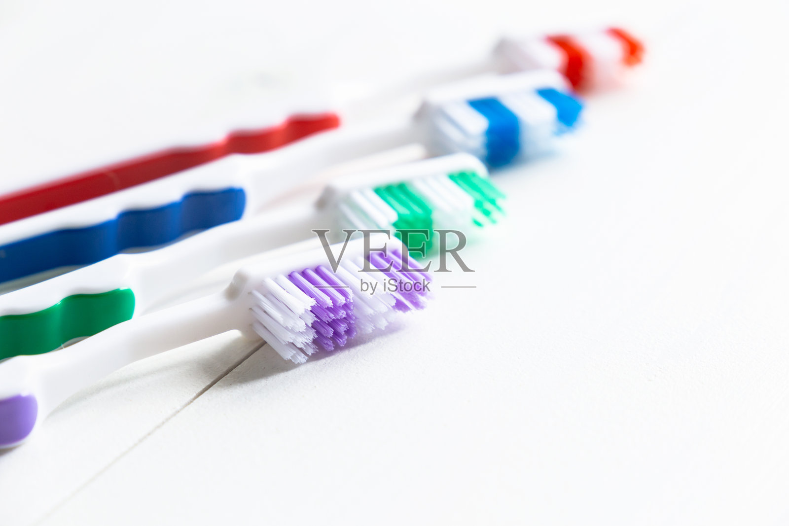 多色的牙刷在白色的背景上排成一排。本空间照片摄影图片
