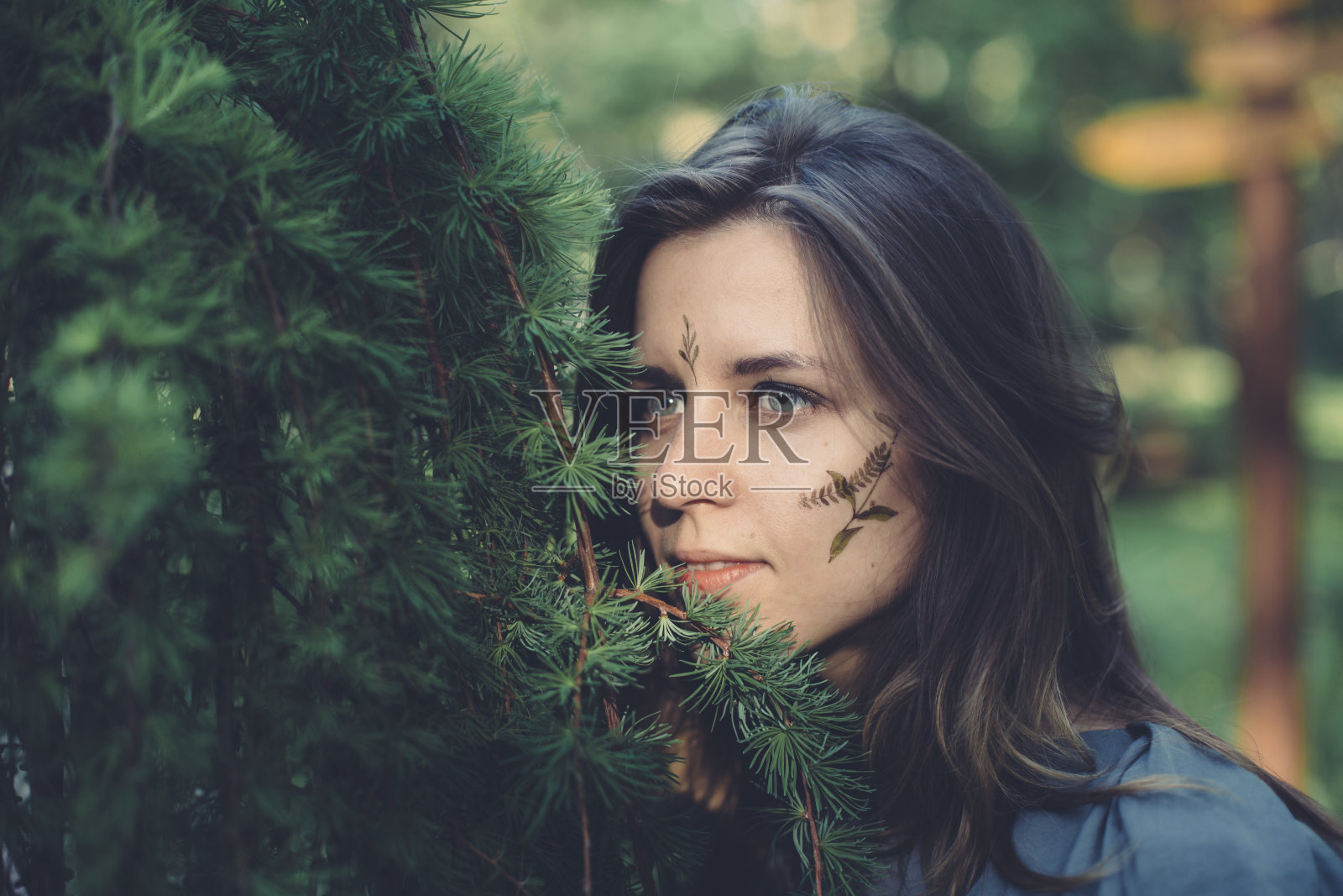 一个年轻女孩的肖像与树叶和植物标本室室外旁边的一棵树照片摄影图片