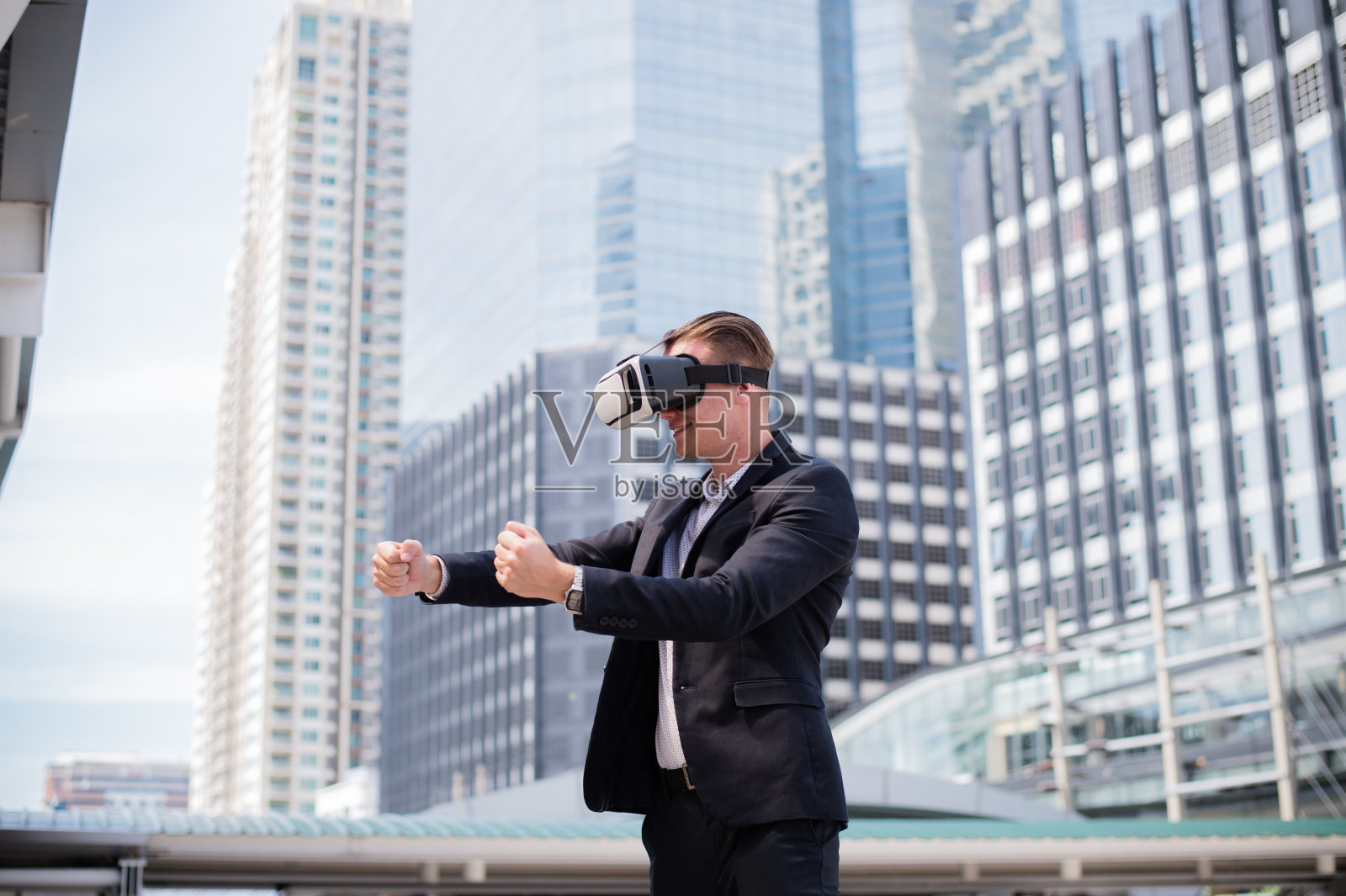 白人商人穿着黑色西装和虚拟现实头盔(VR)，想象赛车。照片摄影图片