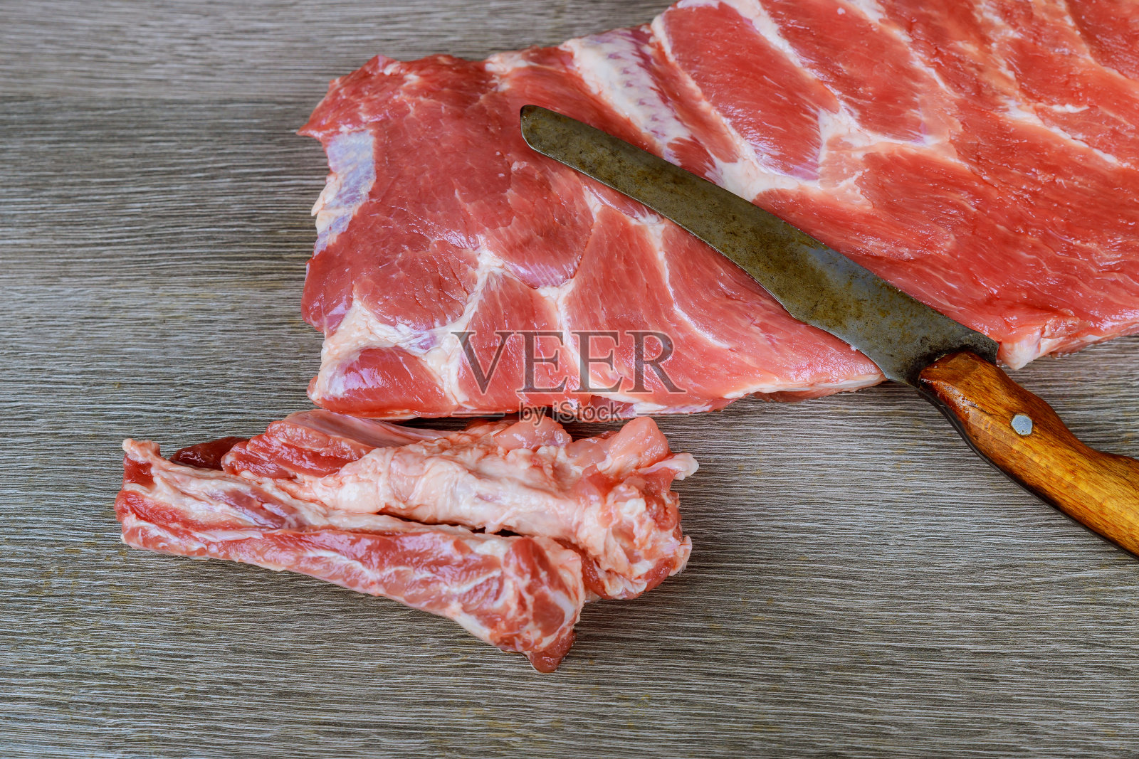 新鲜的生猪肉块在木板上与质朴的金属屠夫照片摄影图片