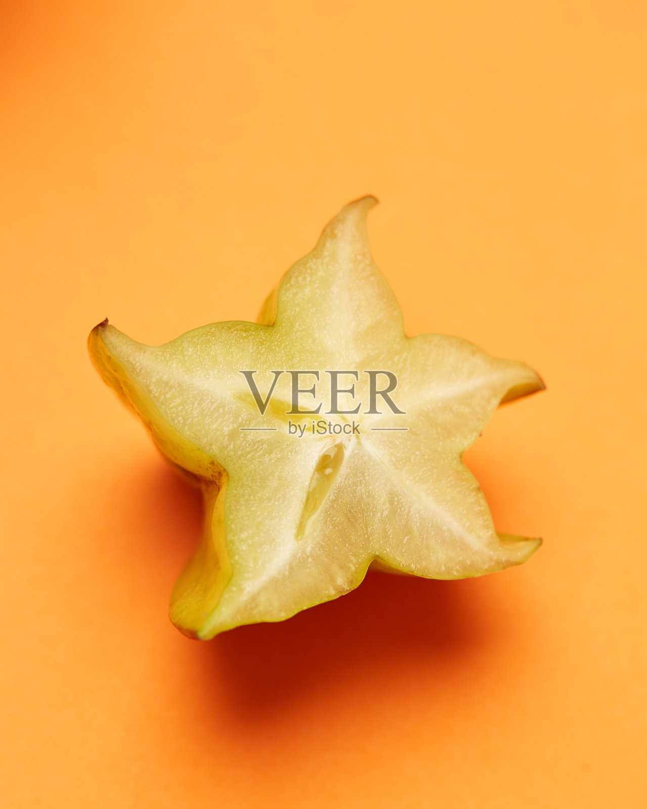 在橙色背景上分离的黄色水果杨桃照片摄影图片