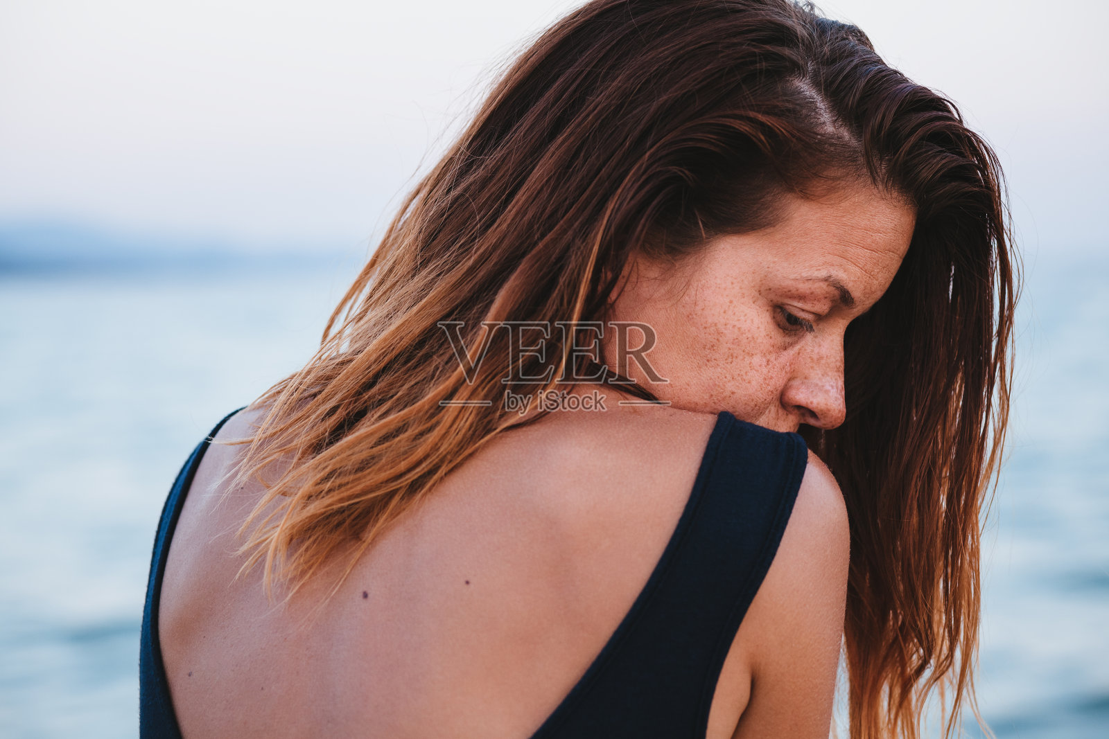 独自一人坐在海滩上，情绪低落的女人照片摄影图片