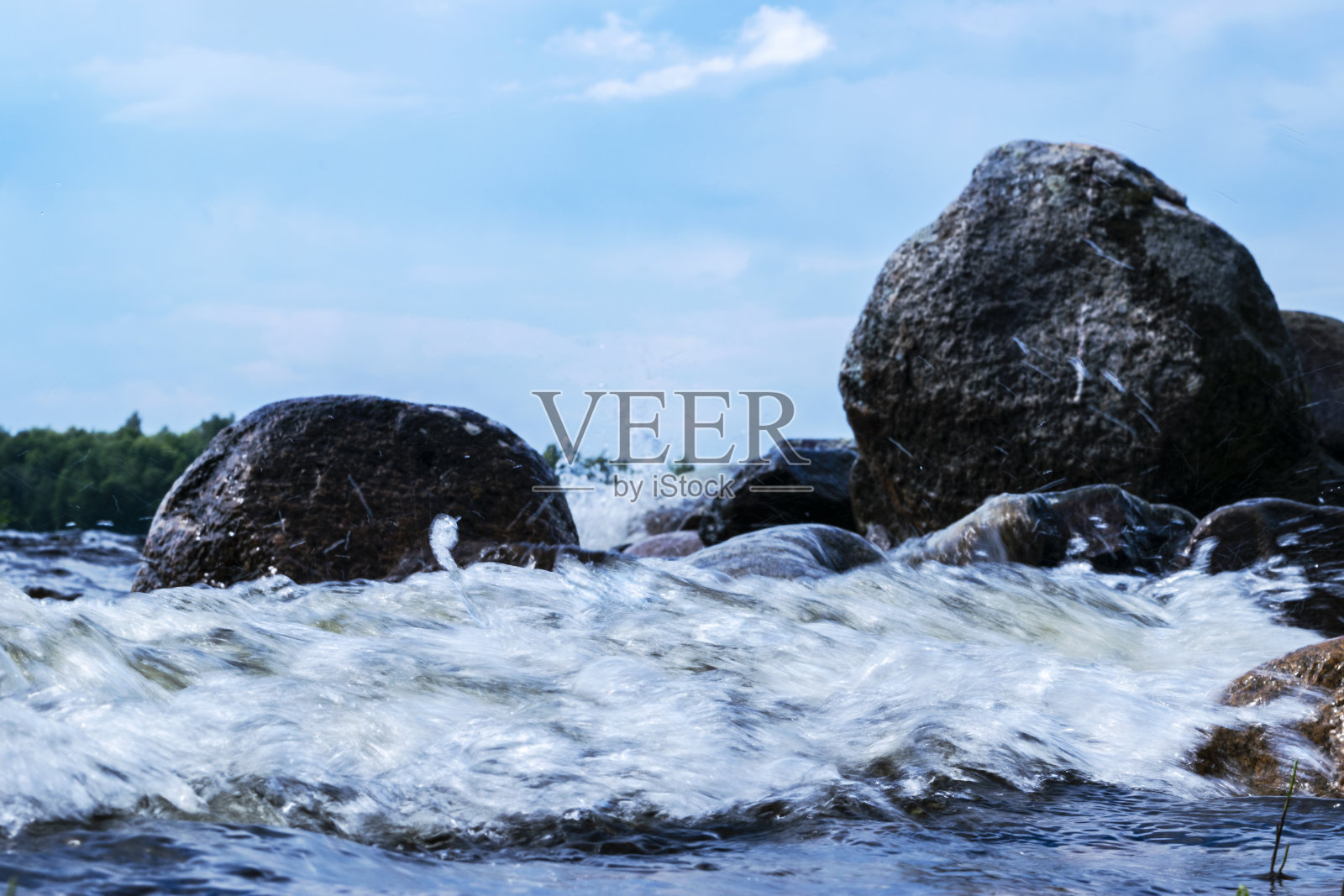 大风的海浪拍打着岩石。湖面上的波浪拍打着海滩。海浪冲击多石的海滩，形成水花。水溅。水表面纹理照片摄影图片