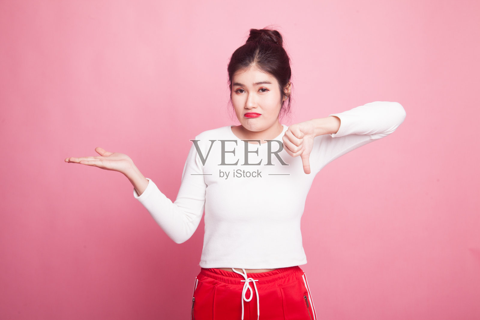 年轻的亚洲妇女显示手掌和拇指向下。照片摄影图片