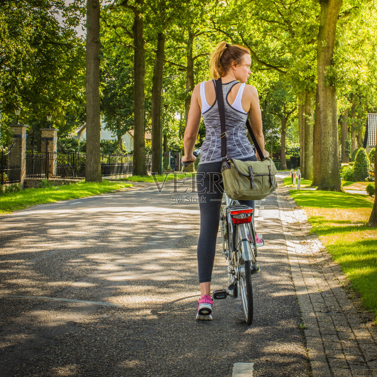 一个运动女孩骑着自行车，背着书包走在乡间小路上。回到学校的概念。照片摄影图片