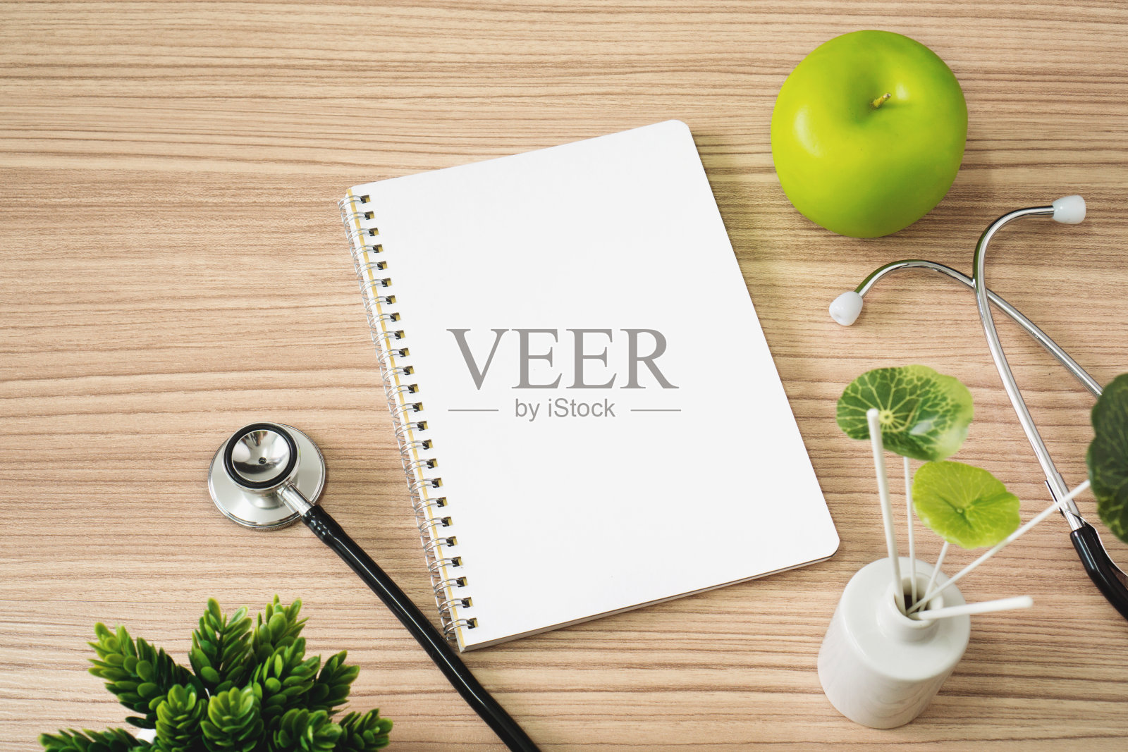 听诊器与笔记本和苹果水果在木材背景。照片摄影图片