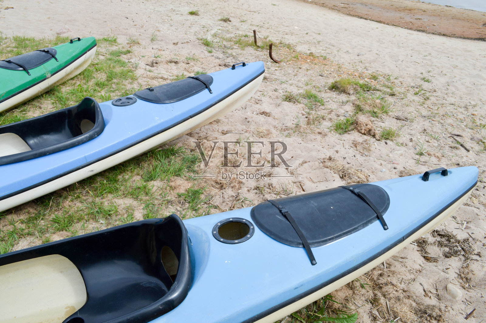 许多蓝色和绿色的皮划艇用前部的鼻子做水上运动，躺在沙滩上游泳照片摄影图片