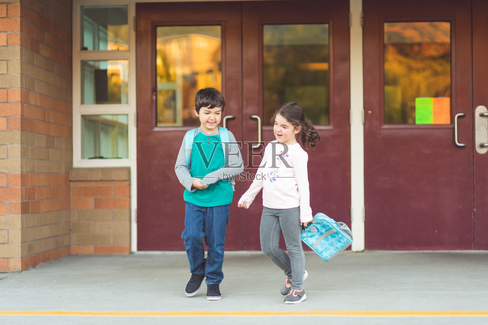 两名小学生走出学校的肖像照片摄影图片