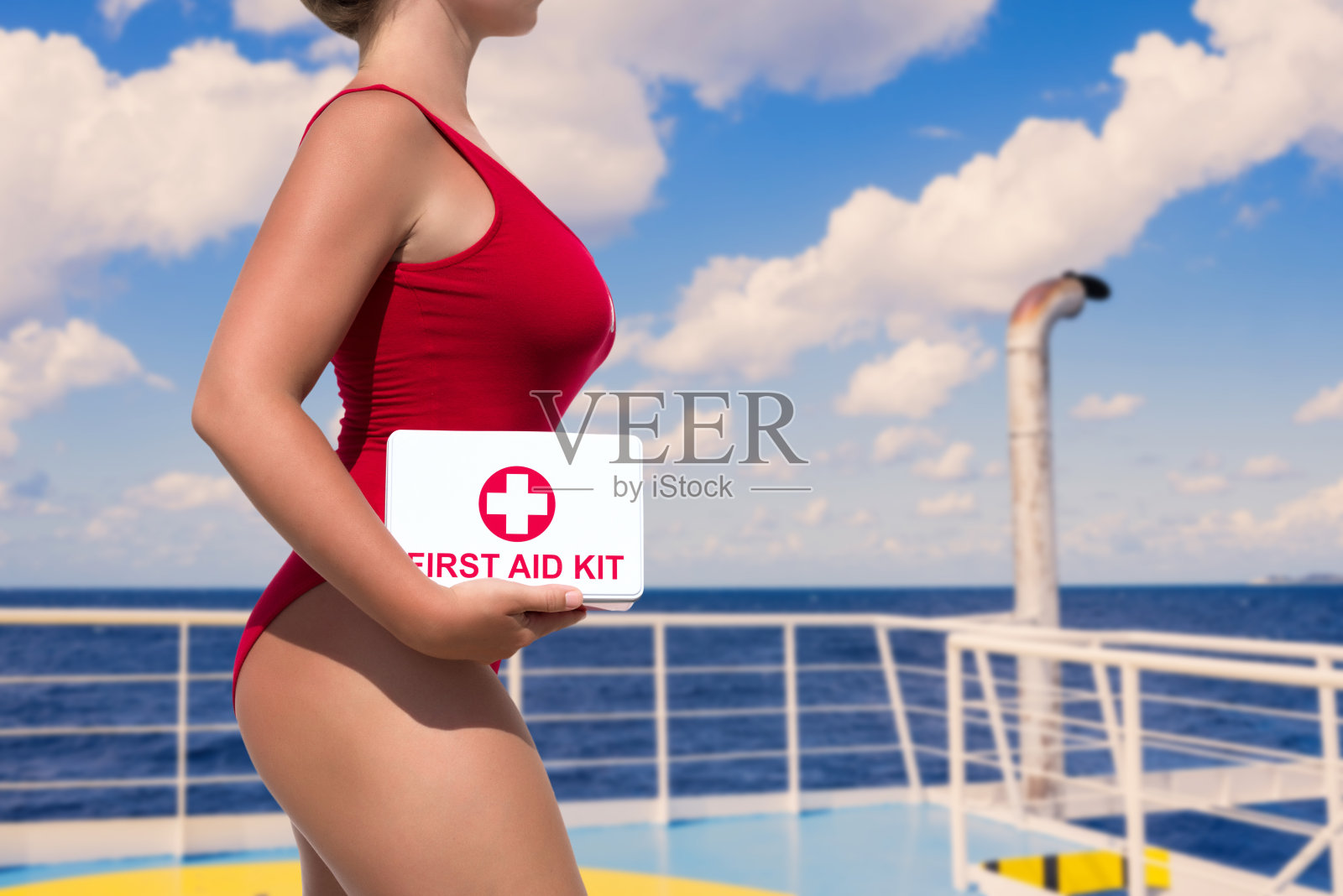 美丽的女子救生员在一个红色的泳衣与一个急救箱在客运渡轮在海上的背景照片摄影图片
