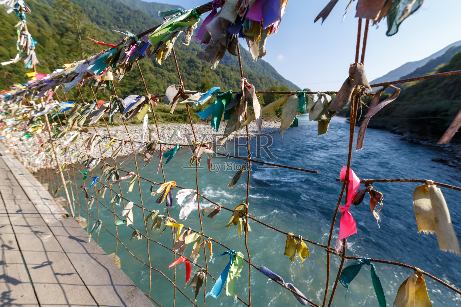 横跨山河的行人吊桥上系着五彩缤纷的彩带照片摄影图片