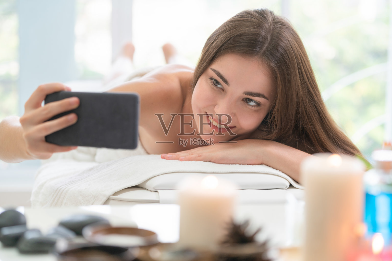 女人躺在水疗床上按摩豪华水疗。照片摄影图片