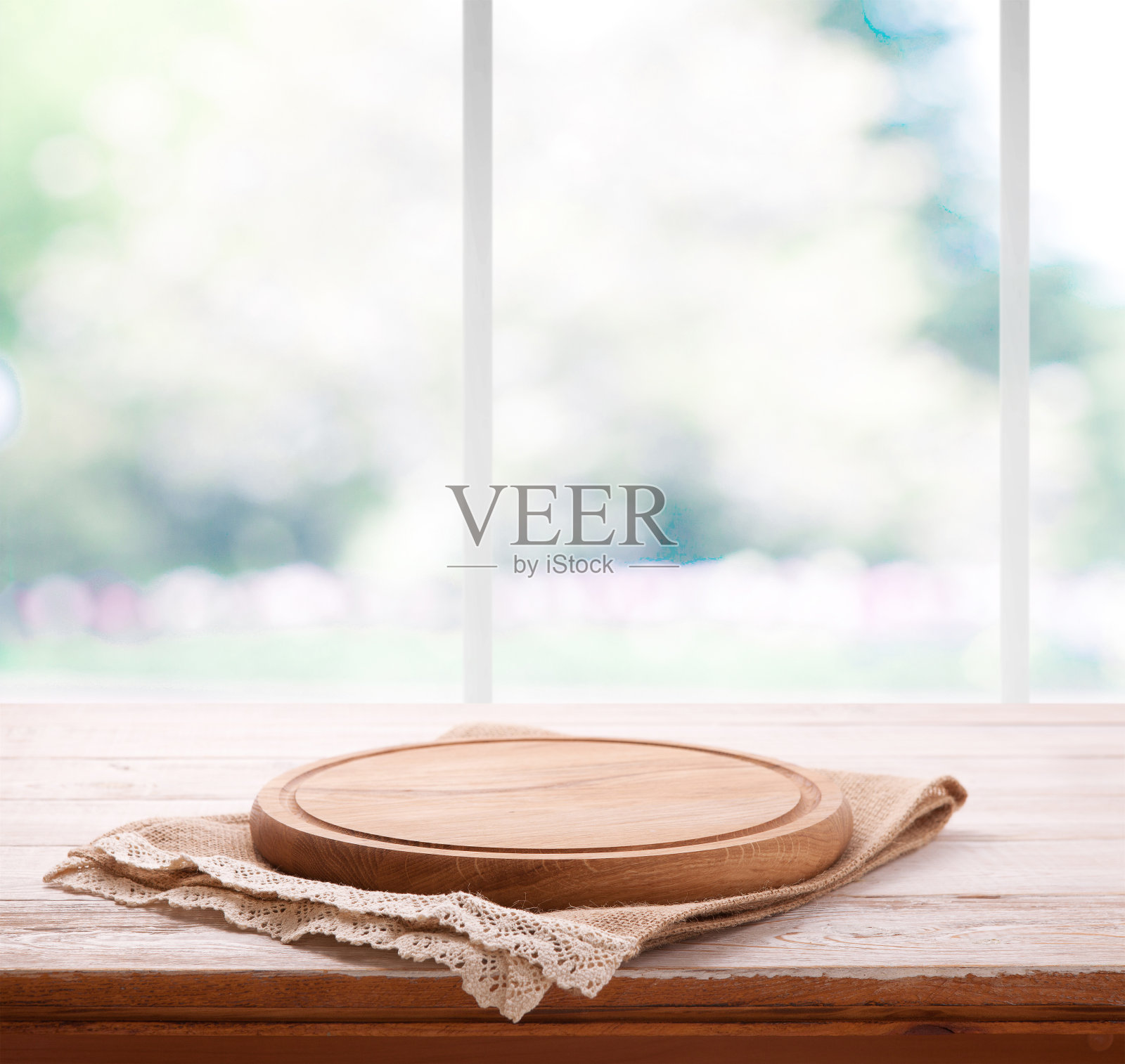 空的木纹比萨饼板和餐巾上的桌子和厨房窗户模糊的背景照片摄影图片