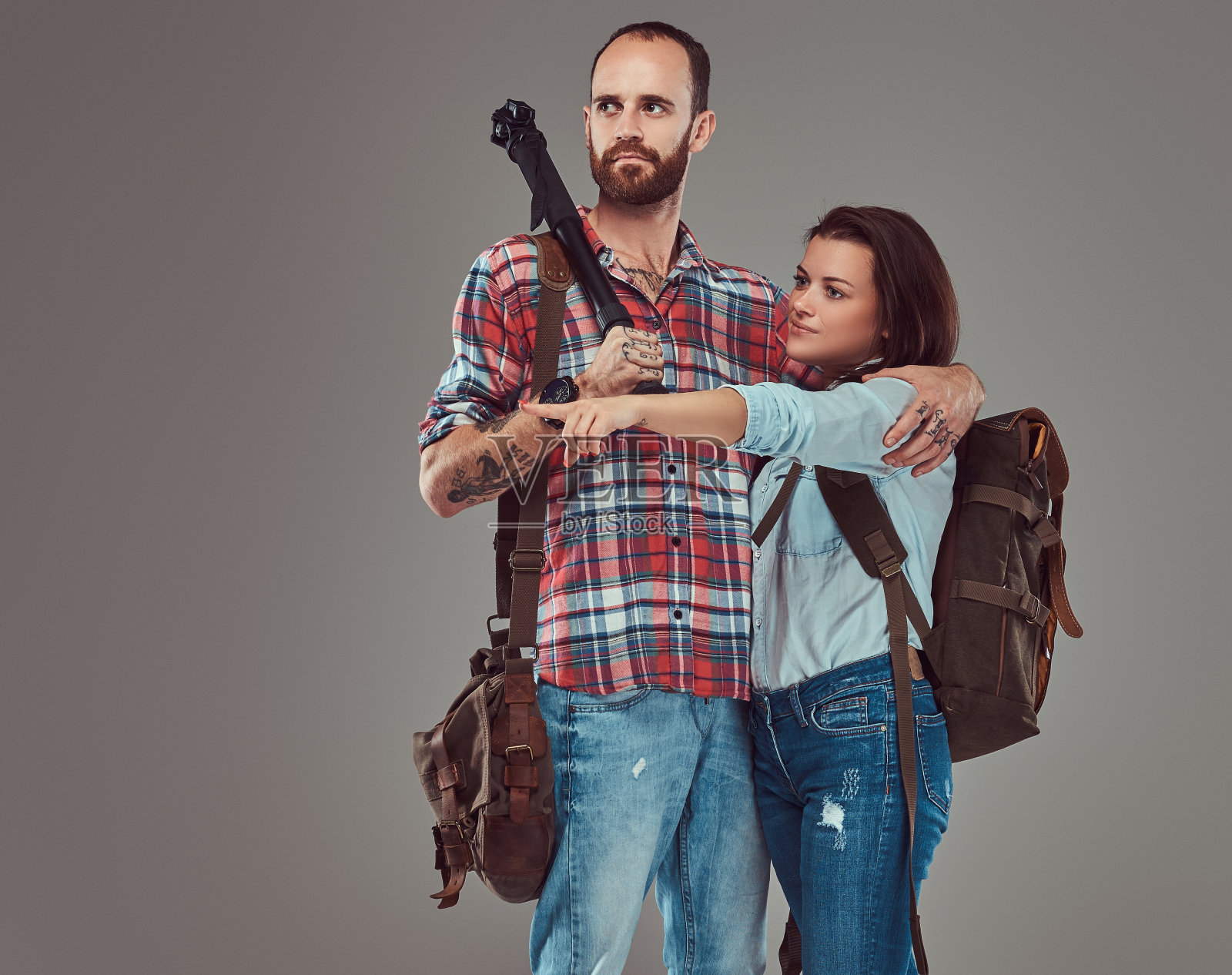 摄影棚里的男女游客背着背包和三脚架，在摄影棚里拥抱在一起。照片摄影图片